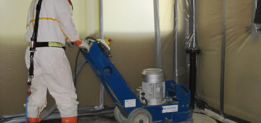 Ponçage d'un sol amianté en zone confinée par un opérateur d'ACD Environnement